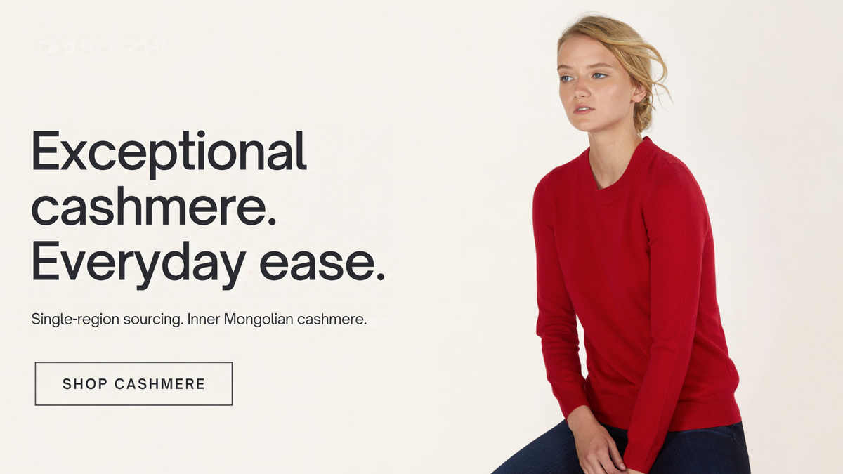 Seated model wearing a JENNIE LIU women's red cashmere crewneck sweater with dark jeans. Exceptional cashmere. Everyday ease. Single-region sourcing from Inner Mongolia.